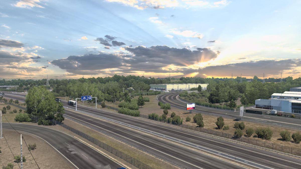 Sun coming through the clouds above a motorway.